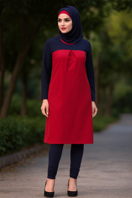 Woman wearing a red and navy outfit standing outdoors with greenery in the background