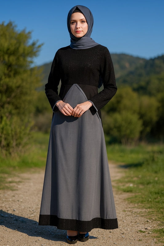 Woman wearing a black top and gray skirt with a headscarf, standing outdoors with mountains in the background.