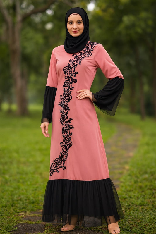 Woman wearing a pink dress with black embroidery and sleeves in a natural setting