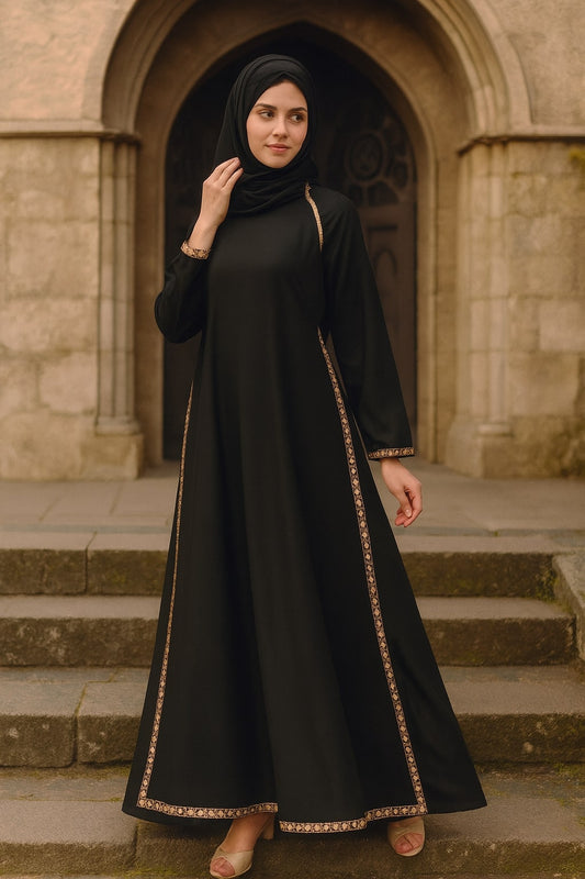 Woman in a black abaya with gold trim standing in front of a stone archway.