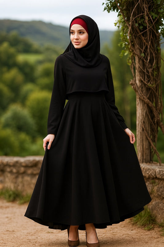 Woman wearing a black hijab and dress standing outdoors with greenery in the background