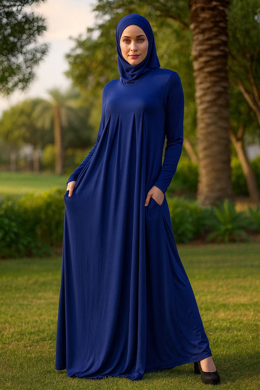 Woman wearing a blue dress standing in a park with trees and grass in the background