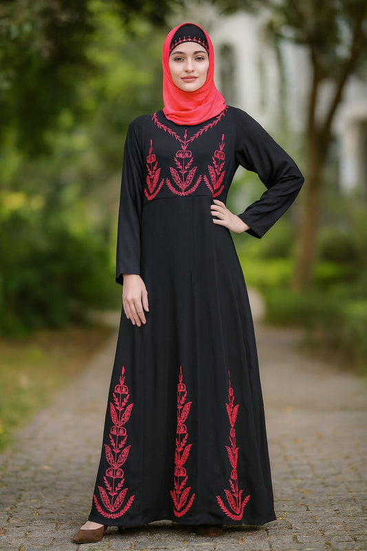 Woman wearing a black dress with red embroidery in an outdoor setting