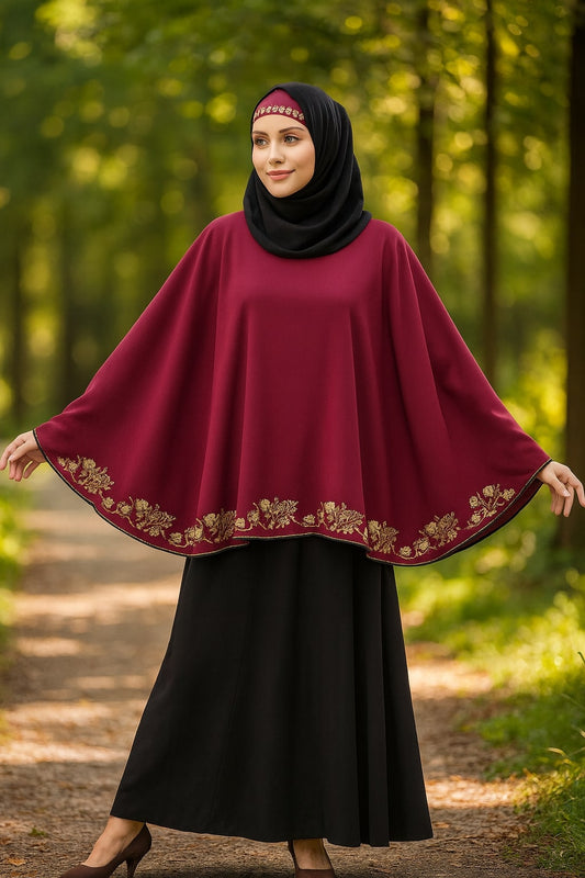 Woman wearing a burgundy poncho with gold embroidery in a forest setting