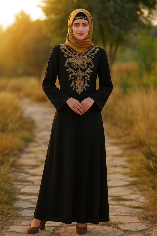 Woman in a black dress with gold embroidery standing on a stone path in a natural setting.