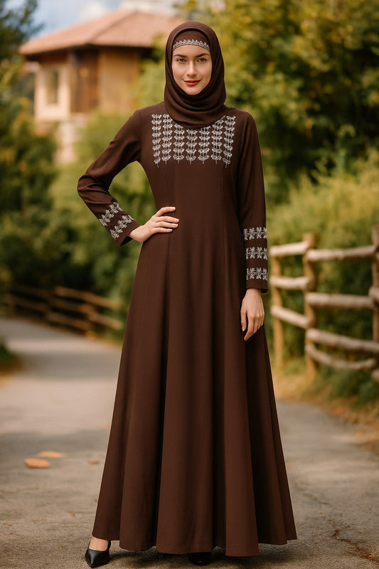 Woman wearing a brown dress with white embroidery in an outdoor setting