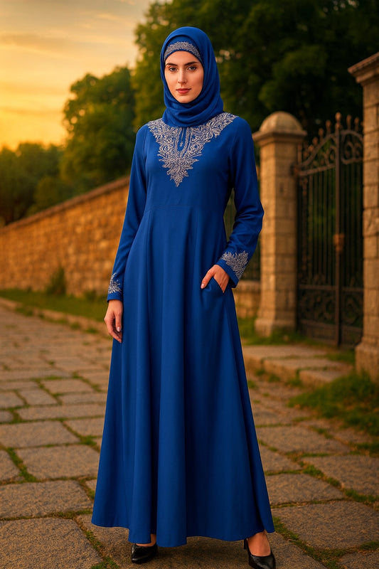 Woman in a blue dress with intricate silver embroidery standing outdoors.