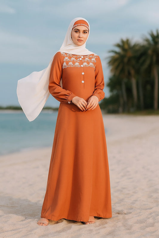 Woman in an orange dress with white lace details standing on a beach.