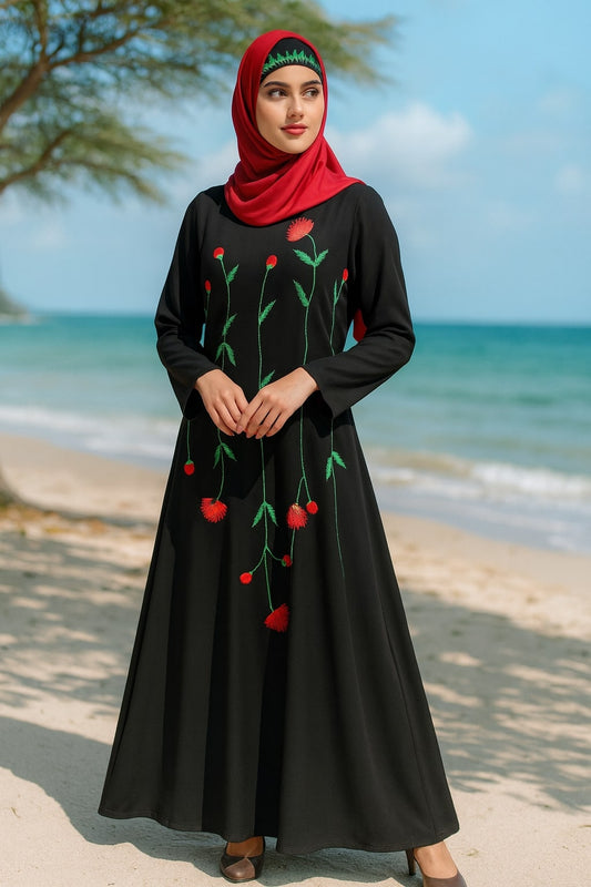 Woman wearing a black dress with red floral patterns on a beach