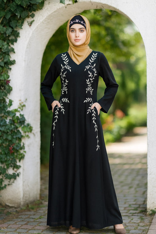 Woman wearing a black dress with white embroidery standing in front of a stone archway.