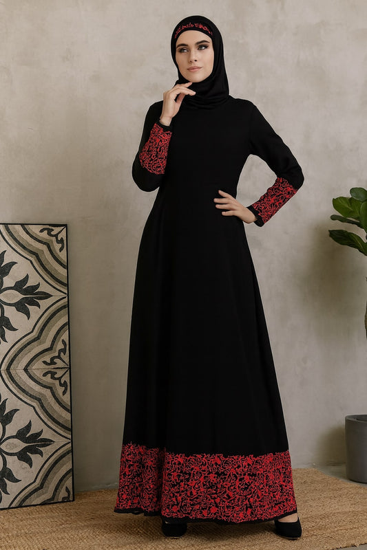 Woman wearing a black dress with red patterns in a room setting.