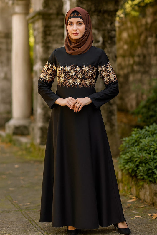 Woman wearing a black dress with gold patterns and a brown hijab standing outdoors.