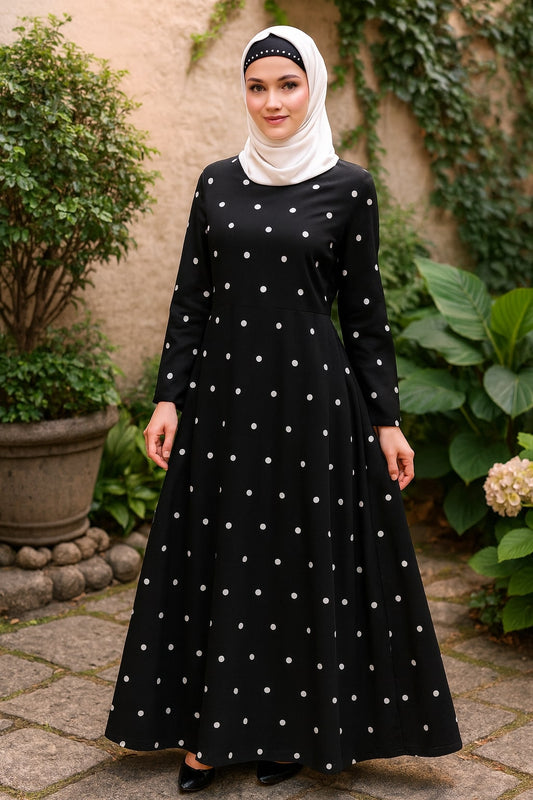 Woman wearing a black dress with white polka dots and a hijab outdoors.