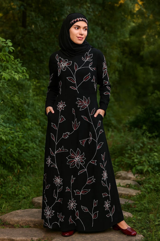 Woman wearing a black abaya with floral embroidery standing outdoors.