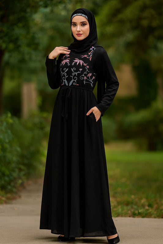 Woman wearing a black dress with floral embroidery in an outdoor setting