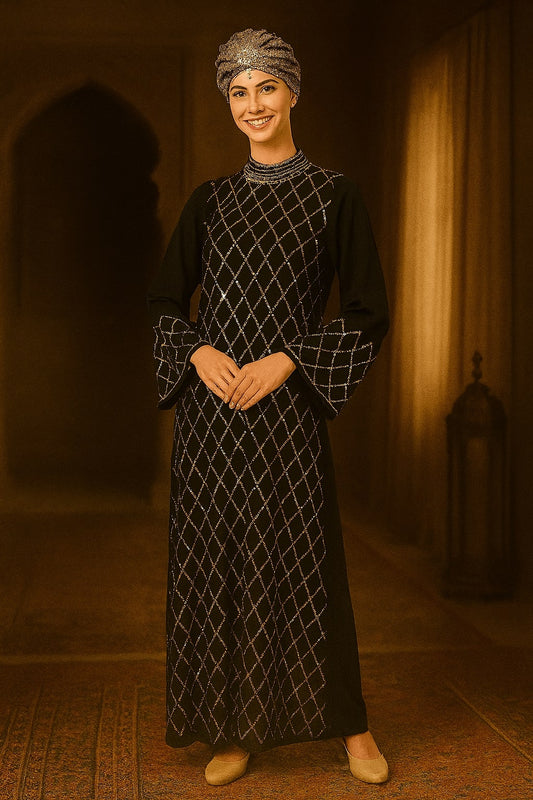 Woman in a black and white patterned dress standing in a warm-toned room.