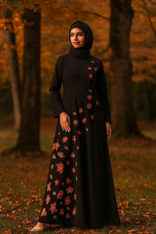 Woman in a black dress with floral patterns standing in an autumnal forest.