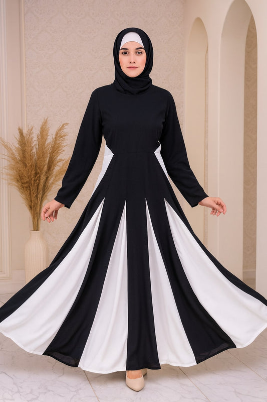 Woman wearing a black and white dress with a hijab in an elegant indoor setting.