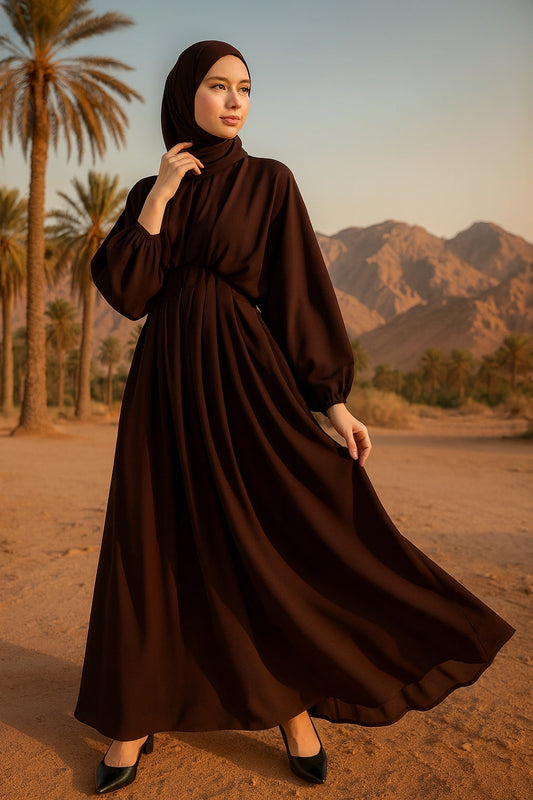 Woman in a brown dress standing in a desert with palm trees and mountains in the background