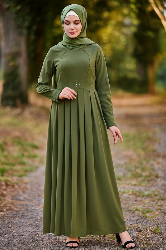 Woman wearing a green hijab and dress standing outdoors with trees in the background