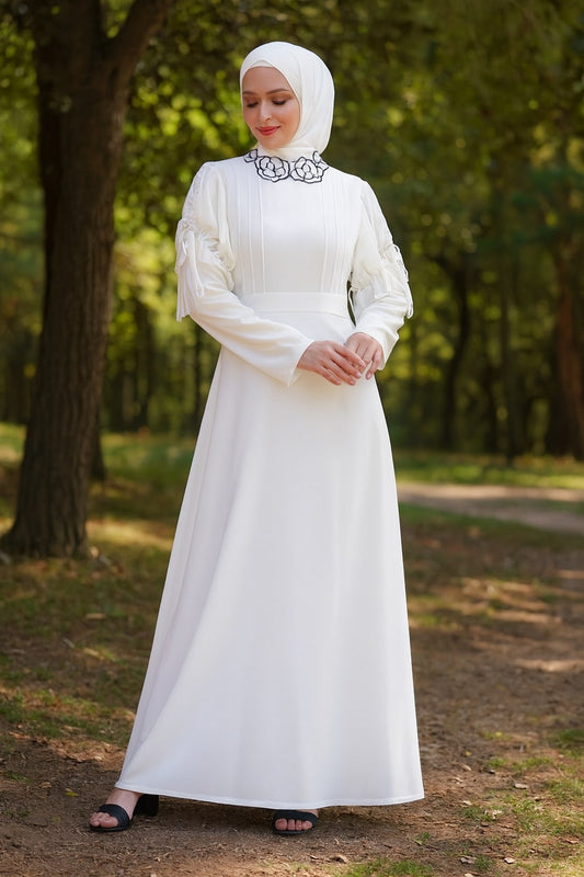 Woman in a white dress and hijab standing in a forest