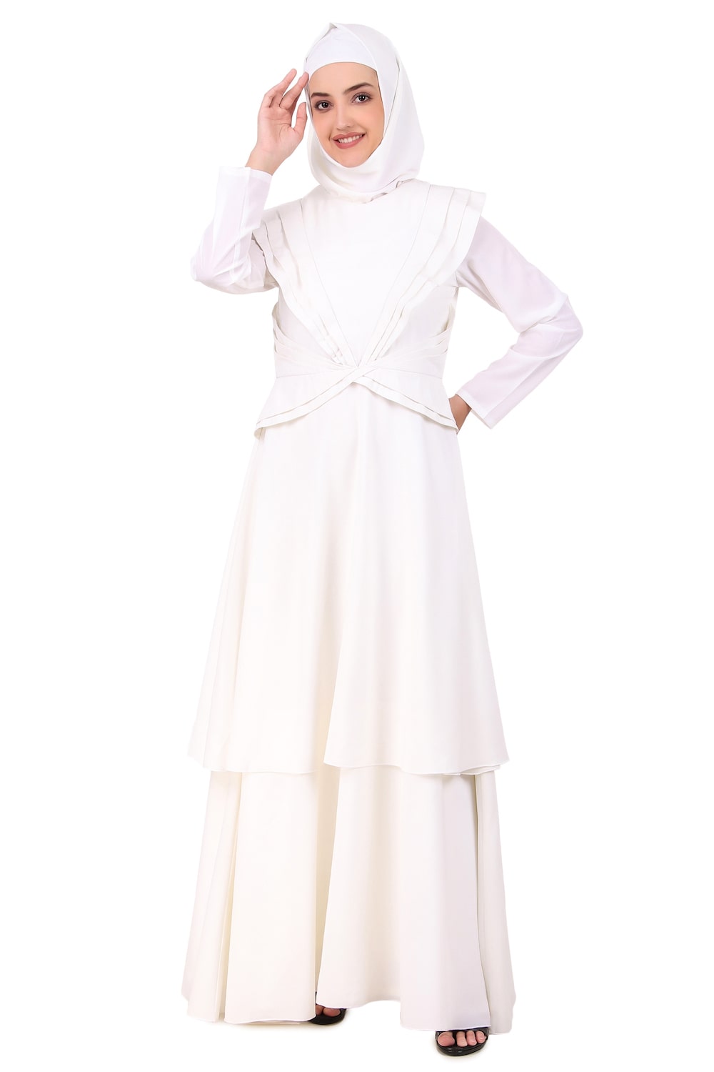 A woman wearing a white traditional abaya with pleated details on the bodice and waist, and a round neckline with a zipper at the back. She is also wearing a matching headscarf.