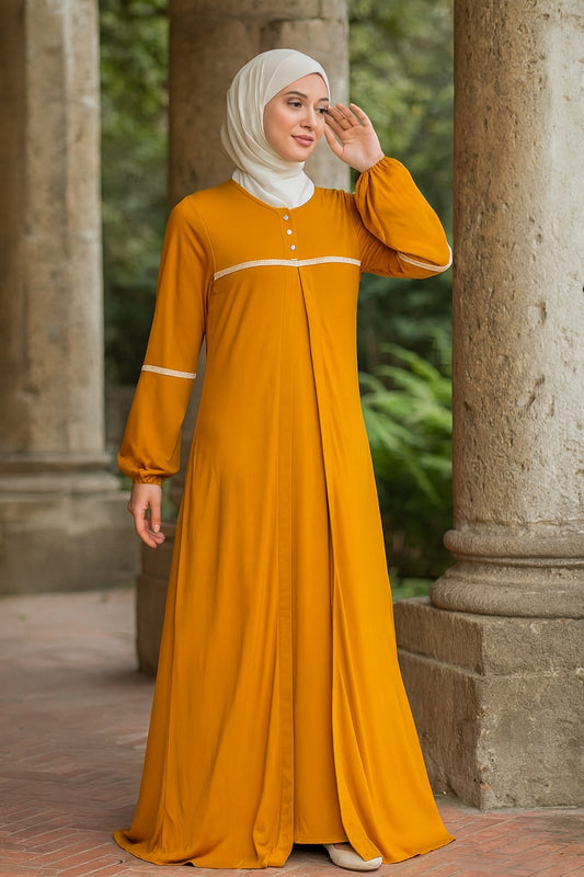 Woman in a mustard yellow dress standing outdoors with stone columns and greenery in the background