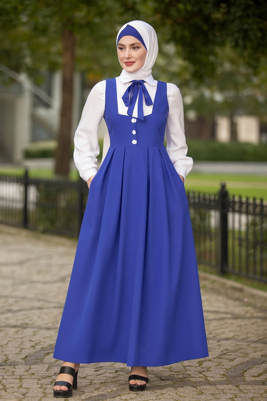 Woman wearing a blue dress with a white blouse and hijab outdoors.