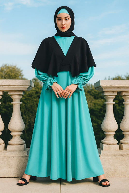 Woman wearing a turquoise dress with a black hijab standing outdoors.
