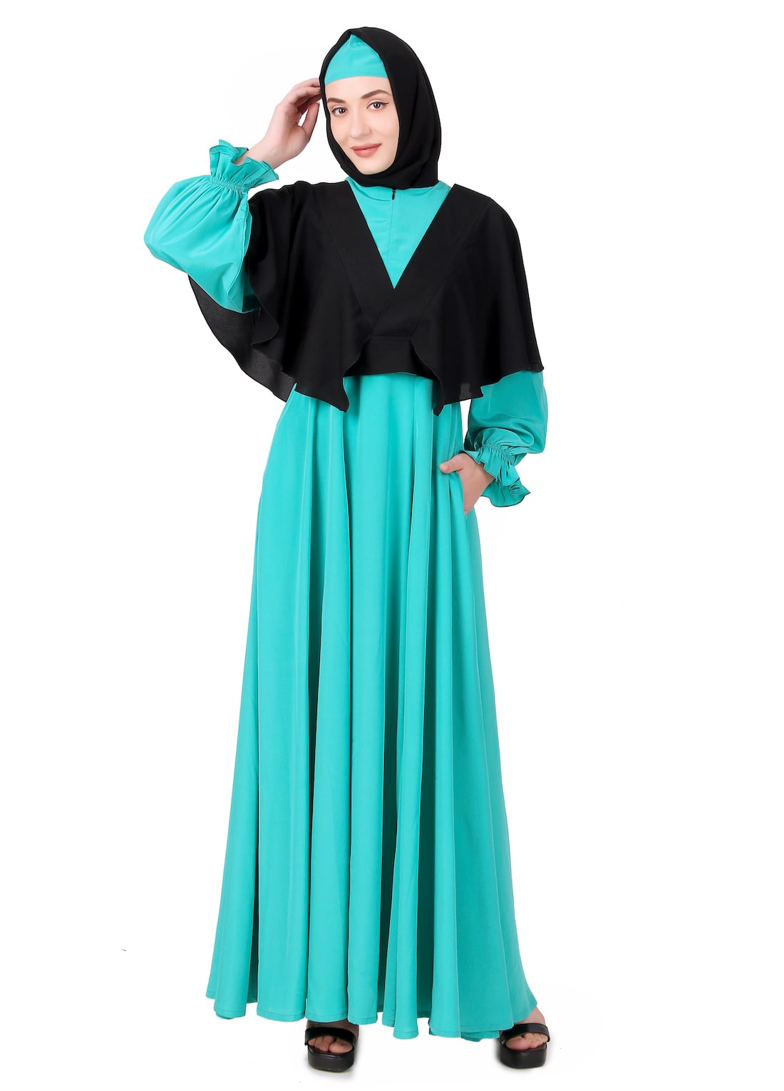 A model wearing a black and turquoise green frilled removable jacket with a flared abaya. The outfit includes a round neck with a zipper, straight sleeves with frilled hem, and utility pockets.