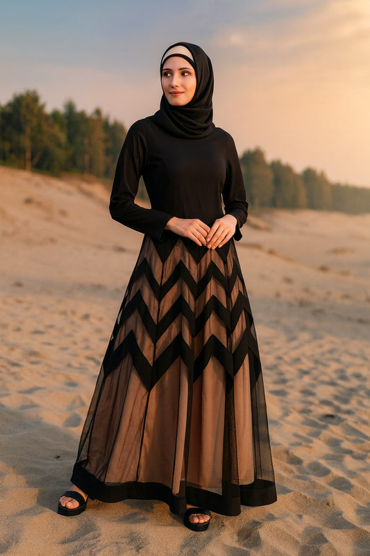Woman in a black and brown dress standing on a sandy landscape with trees in the background