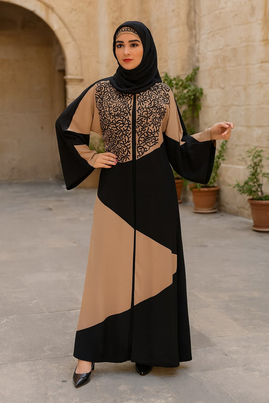 Woman wearing a black and beige dress with a hijab in an outdoor setting.