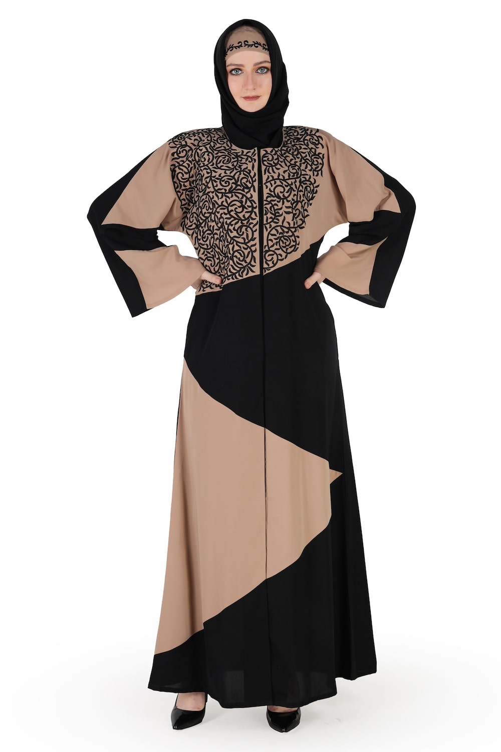 A model wearing a Dubai abaya in warm grey and black with floral embroidery on the top panel, straight sleeves, and a round neckline. The abaya has a front open with snap button closure and utility seam pockets.