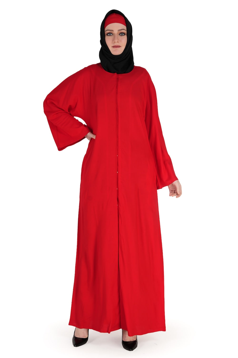 A woman wearing a red Waseemah Rayon Dubai Abaya with a mandarin collar, straight sleeves, and utility seam pockets. The abaya is fully visible, displaying a front open with snap button closure.
