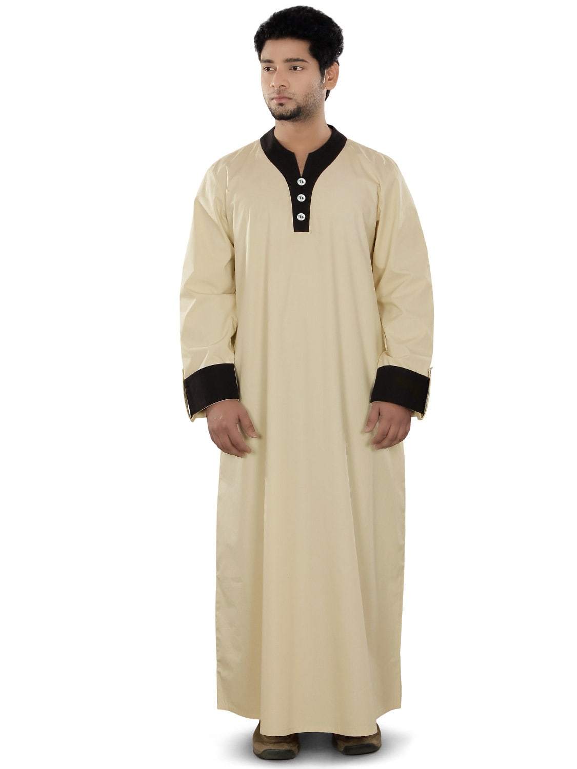 A male model wearing a beige traditional galabiyya with round v-cut neck, dummy buttons, utility pockets, and folded cuff sleeves with strap button fasteners.