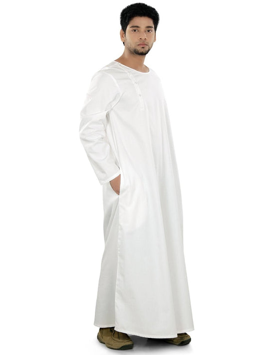 A man wearing a white galabiyya with a round neck, side open placket with buttons, and utility pockets on both sides.