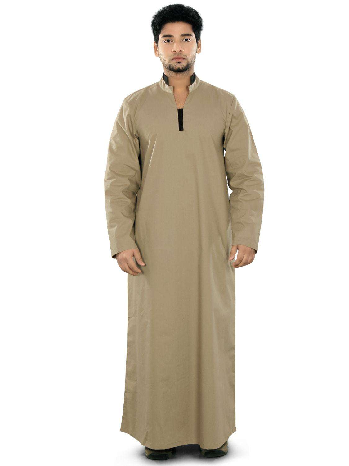 A man wearing a beige ghaniya with a band collar, front open placket, and utility pockets on the sides. The garment appears to be made of a cotton-like fabric.