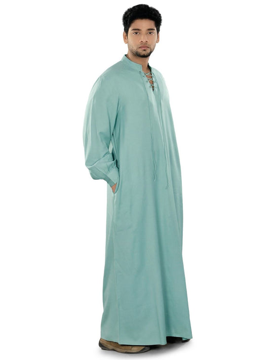 A person wearing a light blue galabiyya with a V-neck collar and front pockets. The fabric appears soft and is likely to be lightweight.