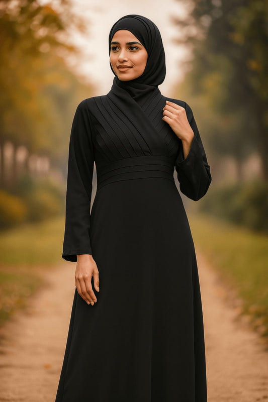 Woman wearing a black hijab and black dress standing outdoors on a path with blurred greenery.