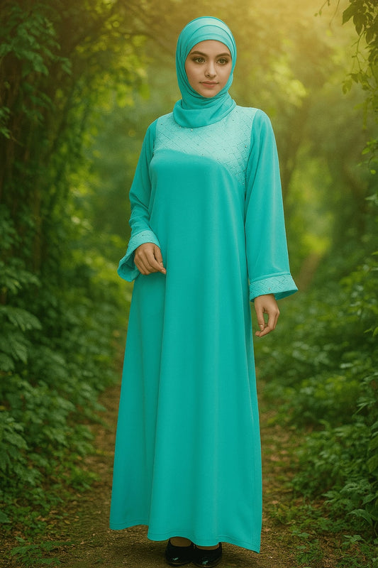 Woman wearing a turquoise dress and hijab standing in a forest