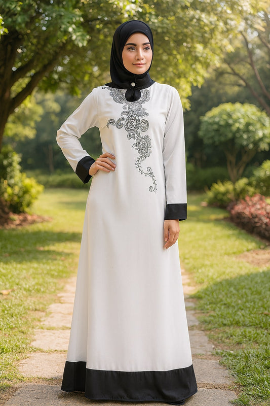 Woman wearing a white dress with black accents in a garden setting