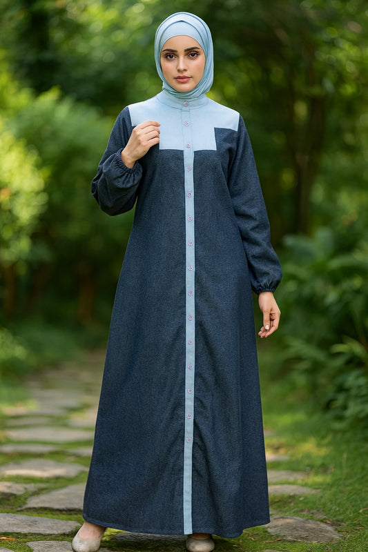 Woman wearing a long dark blue dress with a light blue hijab standing outdoors.