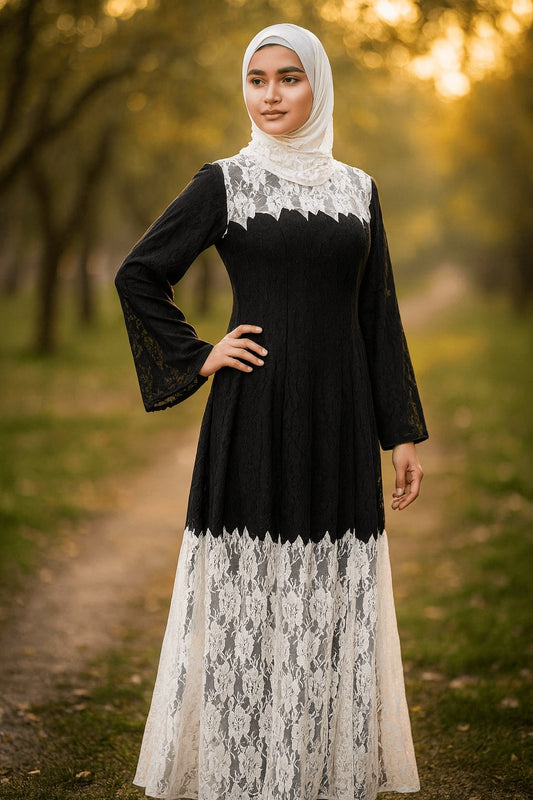Woman wearing a black top with white lace details and a long white skirt in a natural setting.