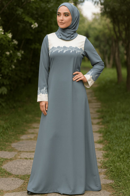 Woman in a gray dress with white lace details standing on a path in a garden.