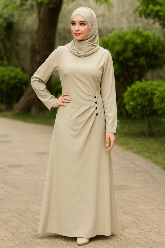 Woman wearing a beige dress with a hijab standing on a pathway with greenery.