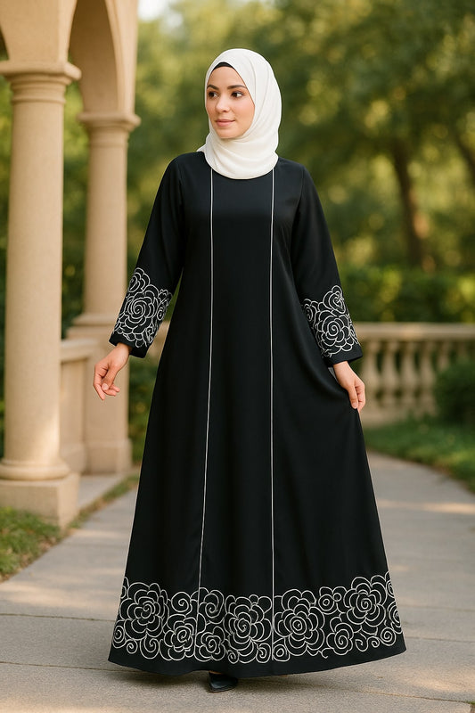 Woman wearing a black dress with white embroidery in an outdoor setting