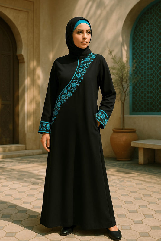 Woman wearing a black dress with blue embroidery in an outdoor setting.