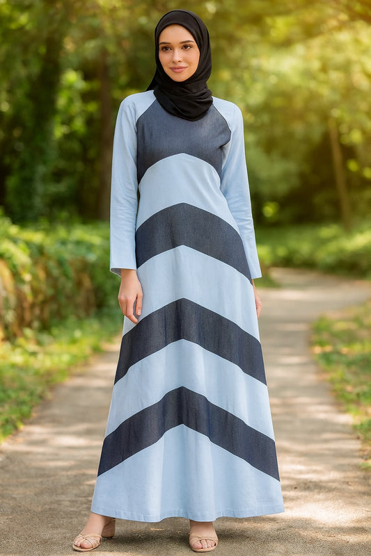 Woman wearing a long, light blue dress with dark gray stripes outdoors.