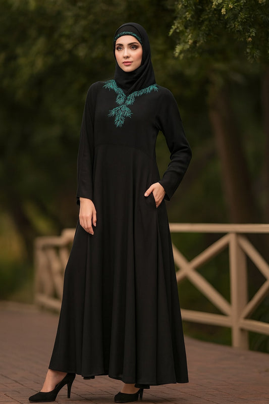 Woman wearing a black dress with green embroidery in an outdoor setting