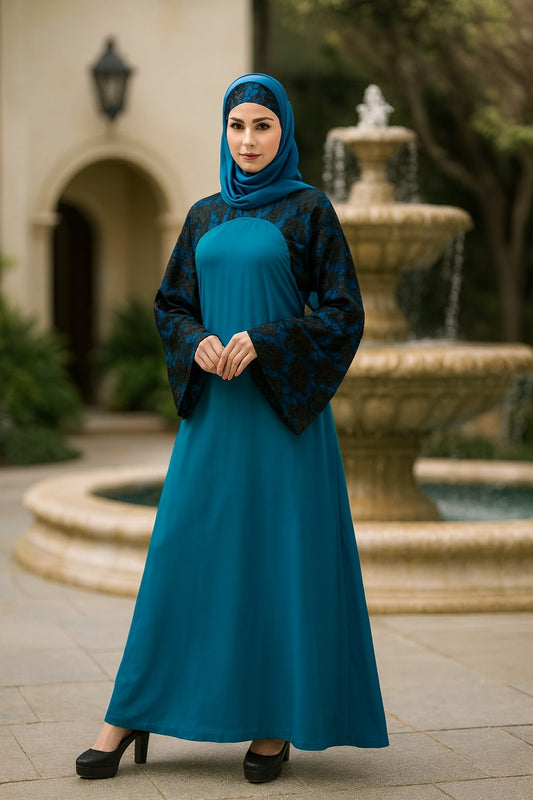 Woman in a teal dress and headscarf standing in front of a fountain.